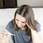 a woman sitting on a couch holding a pen and paper